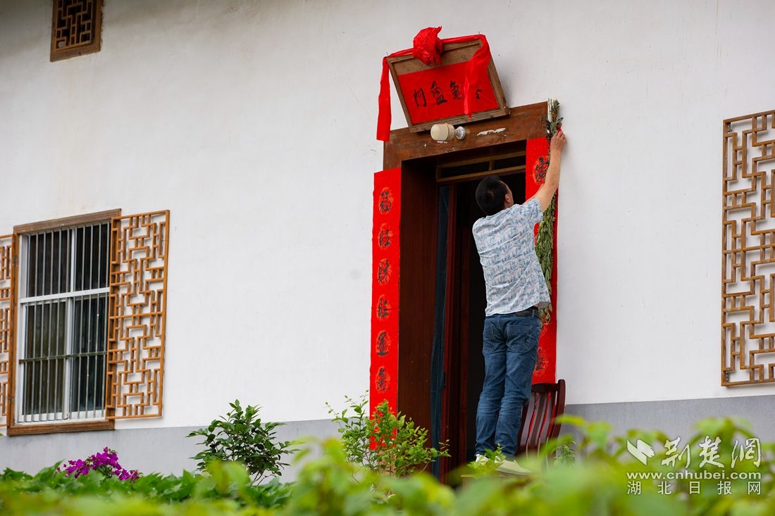 6月11日，在湖北省秭归县九畹溪镇石柱村，当地村民在门前贴端午对联、挂艾蒿。聂爽 摄_副本.jpg.jpg