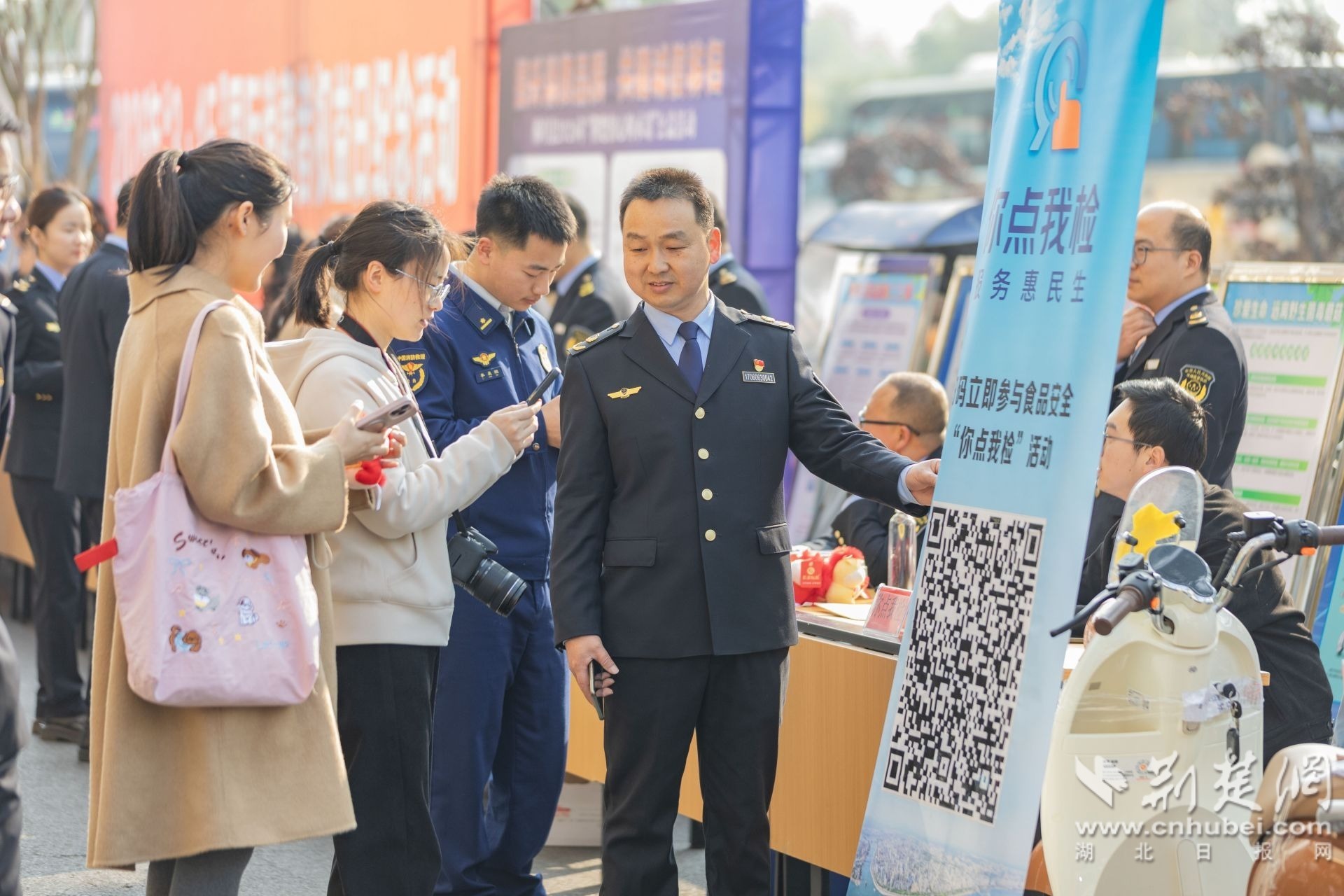 2026年3月13日，湖北省秭归县开展“3·15”国际消费者权益日纪念咨询活动，市民们正现场扫码参与“食品安全‘你点我检’活动”